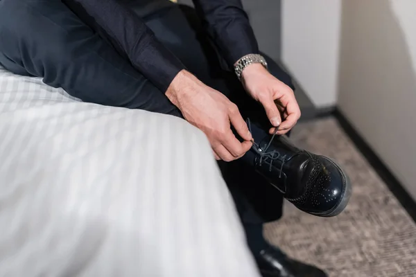 Vista recortada del hombre atando cordones en zapatos en el hotel - foto de stock