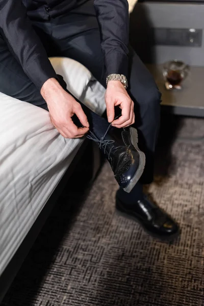 Cropped view of man tying laces on footwear in hotel — Stock Photo