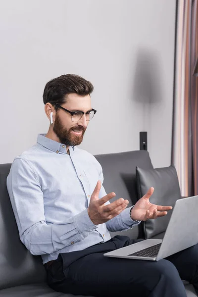 Lächelnder Mann im Augenlicht mit Videoanruf, während er im Hotel auf dem Sofa sitzt — Stockfoto