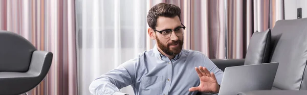 Fröhlicher Mann mit Brille gestikuliert und redet während eines Videogesprächs auf Laptop, Banner — Stockfoto