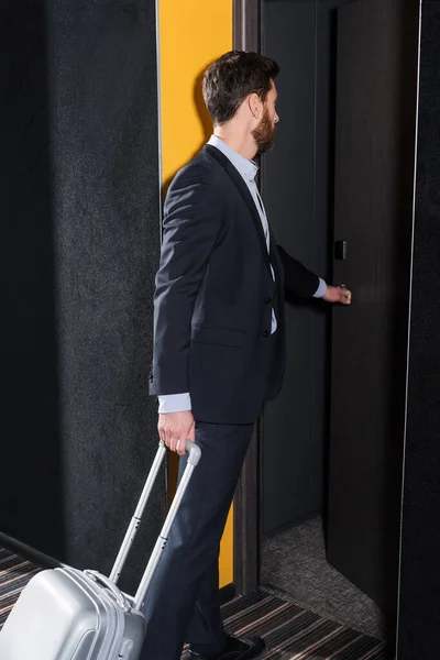 Homem de negócios barbudo com bagagem entrando quarto de hotel — Fotografia de Stock