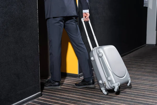 Vista parcial del hombre de negocios con equipaje que entra en la habitación del hotel - foto de stock