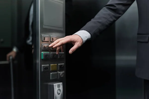 Vista recortada del hombre pulsando el botón en el ascensor moderno - foto de stock