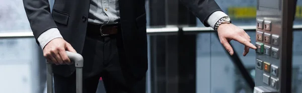 Cropped view of man with baggage pressing button in modern elevator, banner — Stock Photo