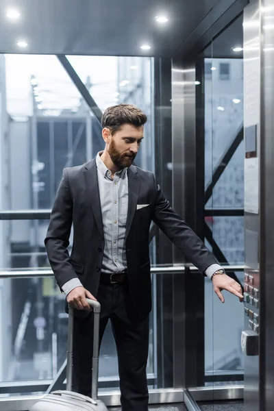 Бородатий чоловік з натисканням кнопки багажу в сучасному ліфті — стокове фото