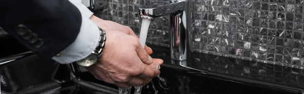 Cropped view of man washing hands in hotel bathroom, banner — Stock Photo