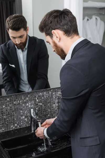 Homme barbu se laver les mains dans la salle de bain moderne à l'hôtel — Photo de stock