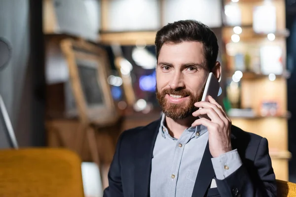 Happy man in suit talking on cellphone in hotel lobby — Stock Photo