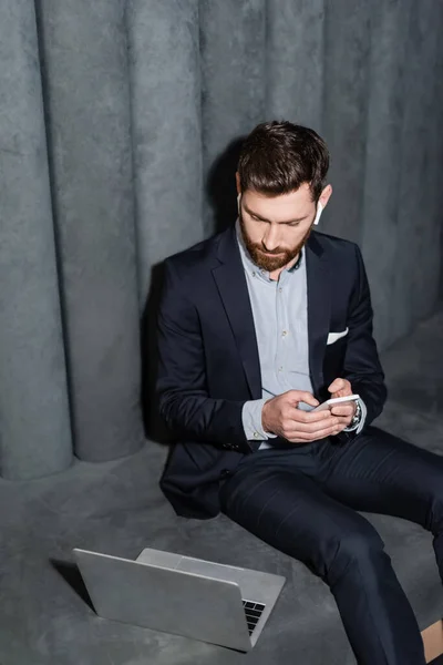 Bearded man in earphones holding smartphone in hotel lobby — Stock Photo