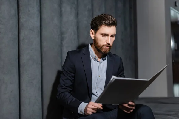 Bearded businessman looking at folder in hotel lobby — Stock Photo