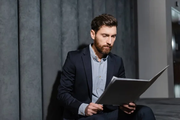 Hombre de negocios barbudo mirando la carpeta en el vestíbulo del hotel — Stock Photo