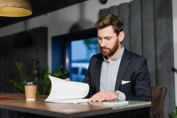 Uomo d'affari in giacca e cravatta guardando i documenti nel caffè dell'hotel — Foto stock