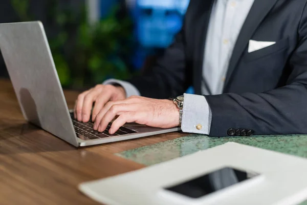 Partial view of man in suit typing on laptop keyboard in hotel lobby, banner — Stock Photo