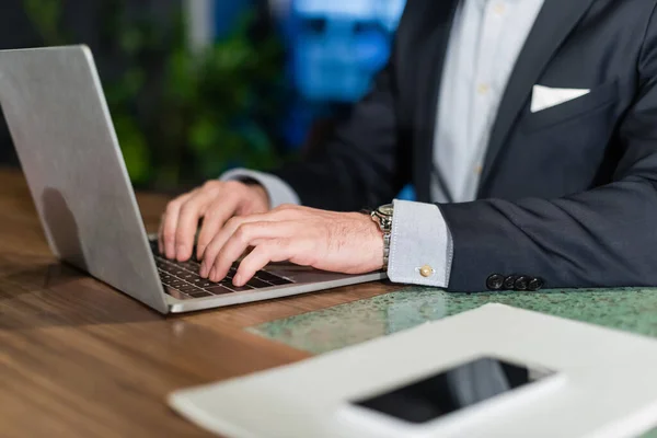 Vue partielle de l'homme en costume tapant sur le clavier de l'ordinateur portable dans le hall de l'hôtel, bannière — Photo de stock