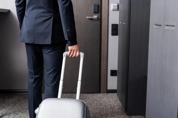 Partial view of businessman in formal wear standing with baggage in hotel room — Stock Photo