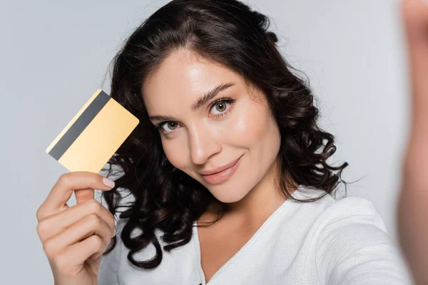 Gioiosa giovane donna in possesso di carta di credito con cashback isolato su grigio — Foto stock