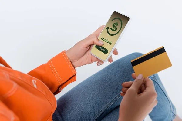 Teilbild einer Frau, die ihr Smartphone mit Bargeld auf dem Bildschirm benutzt und ihre Kreditkarte isoliert auf grau hält — Stockfoto