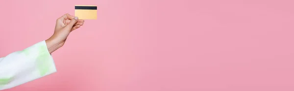 Vista cortada de jovem segurando cartão de crédito isolado em rosa, banner — Fotografia de Stock