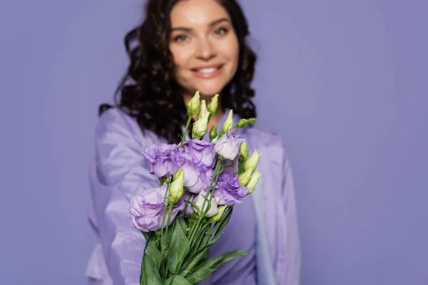 Glücklich verschwommene Frau hält Blumenstrauß isoliert auf lila — Stockfoto