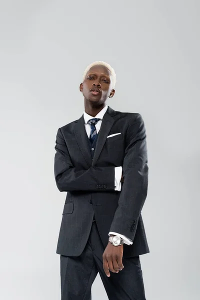Biondo afroamericano uomo d'affari in tuta posa isolato sul grigio — Foto stock