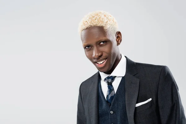 Усміхнений і молодий афроамериканський чоловік у костюмі ізольований на сірому — стокове фото