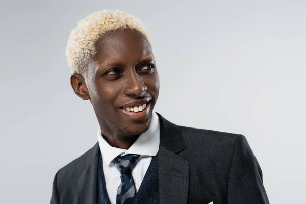 Retrato de hombre afroamericano rubio con ojos azules sonriendo aislado en gris - foto de stock