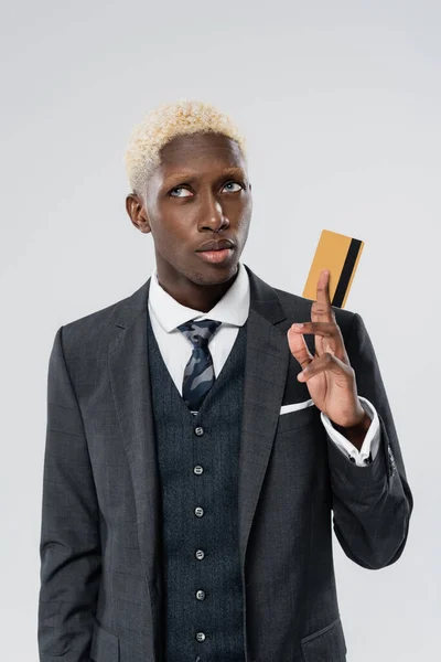 Loira e jovem empresário afro-americano de terno segurando cartão de crédito isolado em cinza — Fotografia de Stock