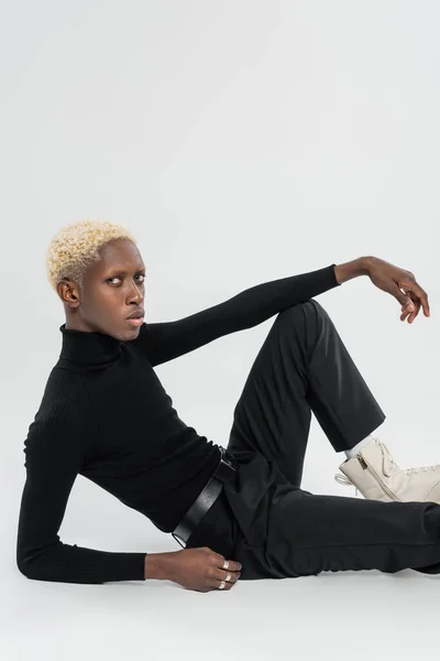 Young and blonde african american man sitting on grey — Stock Photo