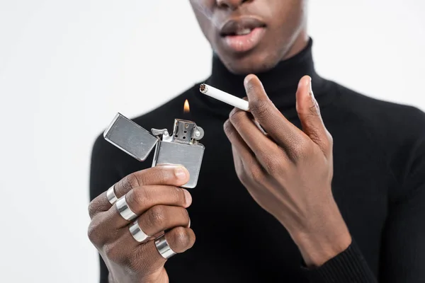 Обрезанный вид африканского американца, держащего зажигалку и сигарету, изолированную на сером — стоковое фото