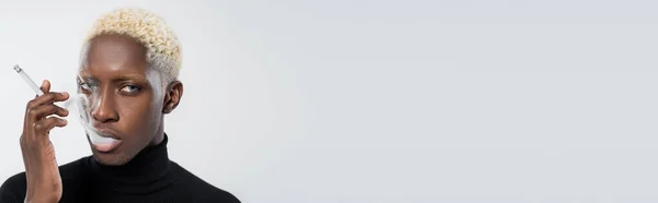 Blond afro-américain aux yeux bleus fumer cigarette isolé sur gris, bannière — Photo de stock