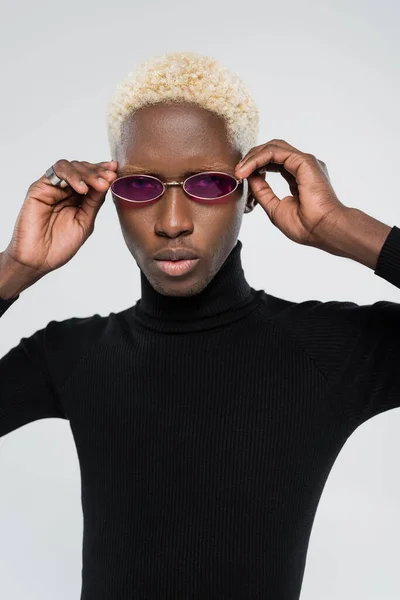 Hombre afroamericano rubio en cuello alto con gafas de sol de color rosa aisladas en gris - foto de stock