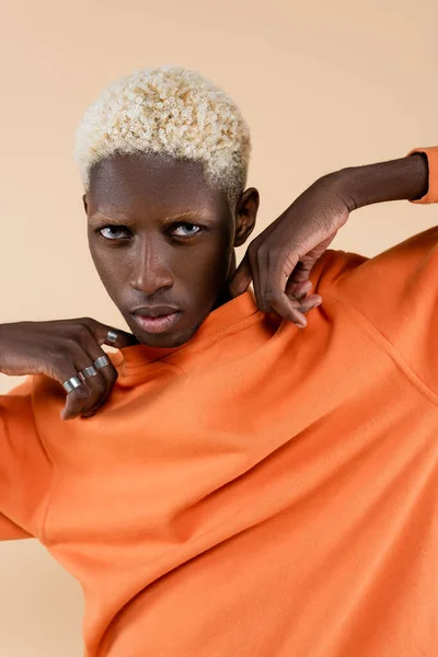 Blonder afrikanisch-amerikanischer Mann mit blauen Augen, der isoliert auf beige in die Kamera blickt — Stockfoto
