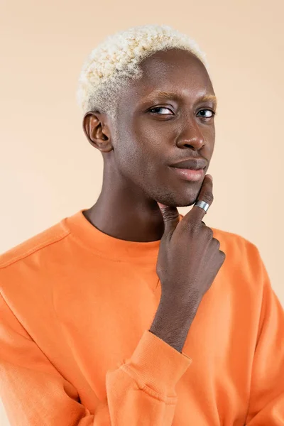 Portrait of pensive african american man in orange sweatshirt looking away isolated on beige — Stock Photo