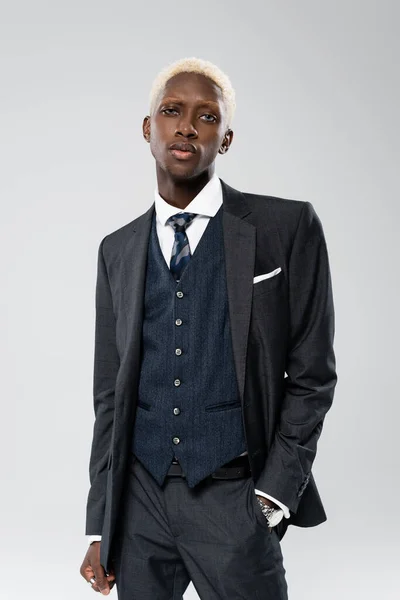 Elegant african american man in formal wear posing with hand in pocket isolated on grey — Stock Photo