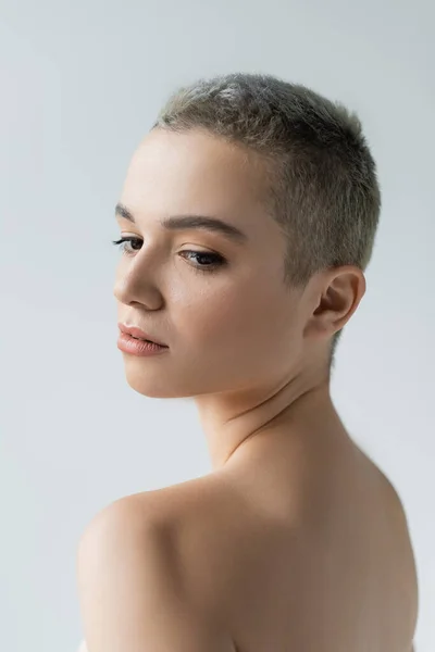 Young woman with short hair and naked shoulders isolated on grey — Stock Photo