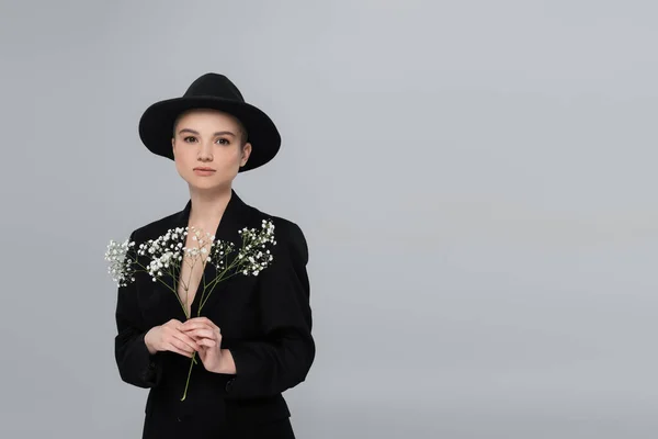 Mulher elegante em blazer preto segurando flores gypsophila isolado em cinza — Fotografia de Stock