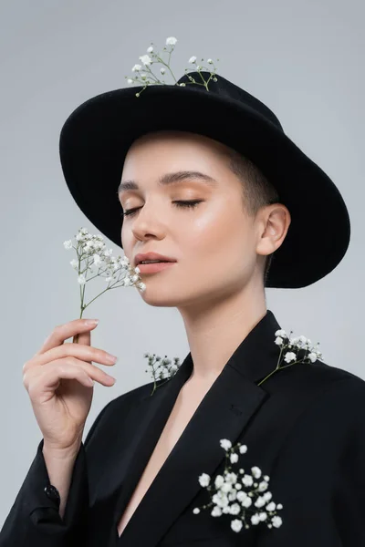 Модна жінка з закритими очима і природним макіяжем, що пахне квітами гіпсофіли ізольовані на сірому — стокове фото