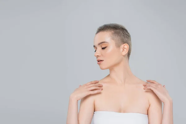 Jeune femme avec les yeux fermés touchant les épaules nues isolé sur gris — Photo de stock