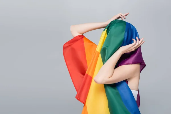 Junge Frau bedeckt Kopf mit lgbt Flagge isoliert auf grau — Stockfoto