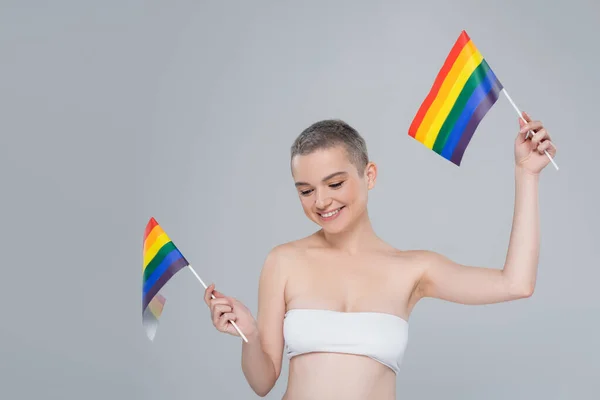 Happy woman in white top posing with small lgbt flags isolated on grey — Stock Photo