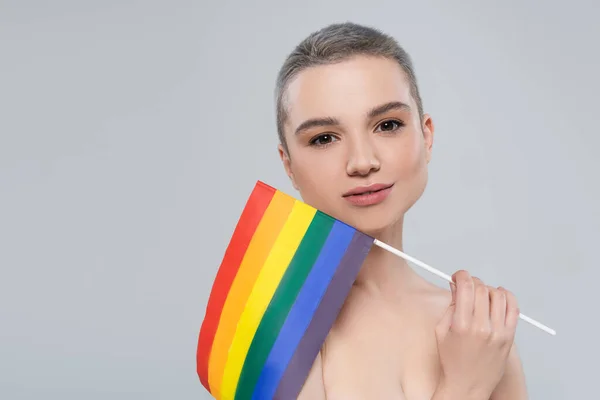 Hübsche Frau mit kleiner lgbt-Fahne blickt vereinzelt in die Kamera auf grau — Stockfoto