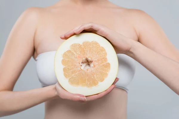 Vista recortada de mujer con la mitad de pomelo maduro aislado en gris - foto de stock