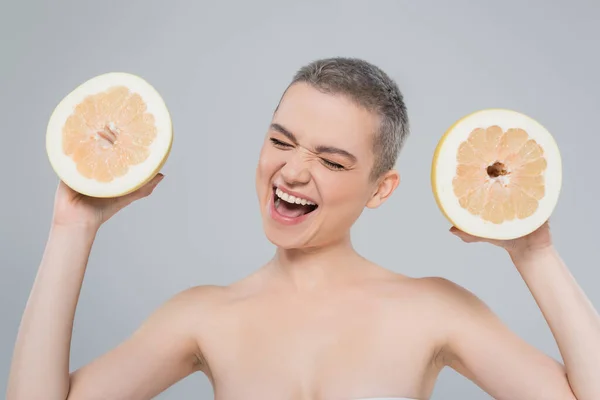 Femme ravie avec une peau parfaite tenant des moitiés de pamplemousse juteux isolé sur gris — Photo de stock