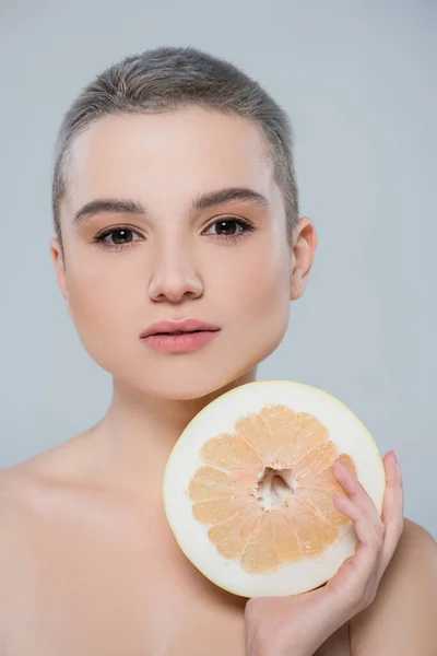 Portrait of pretty woman with short hair looking at camera near half of grapefruit isolated on grey — Stock Photo