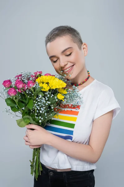Femme souriante portant t-shirt aux couleurs lgbt et tenant un bouquet coloré isolé sur gris — Photo de stock