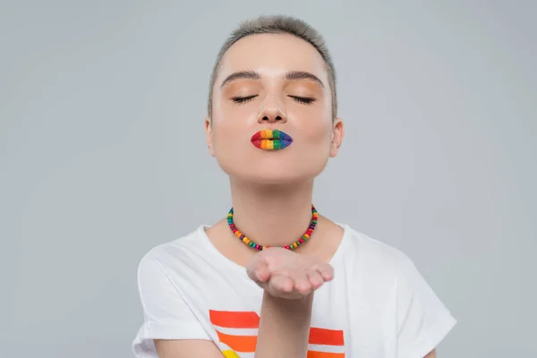 Jeune femme avec lgbt couleurs lèvres soufflage air baiser isolé sur gris — Photo de stock