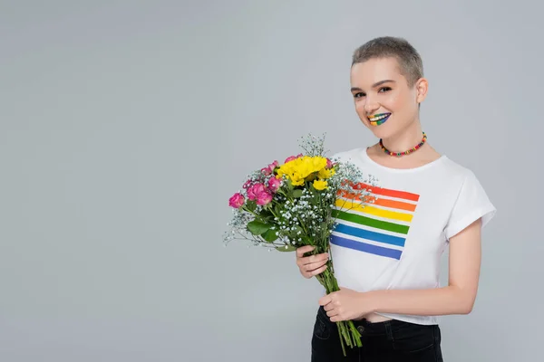 Mujer feliz en arco iris color camiseta celebración colorido ramo aislado en gris - foto de stock