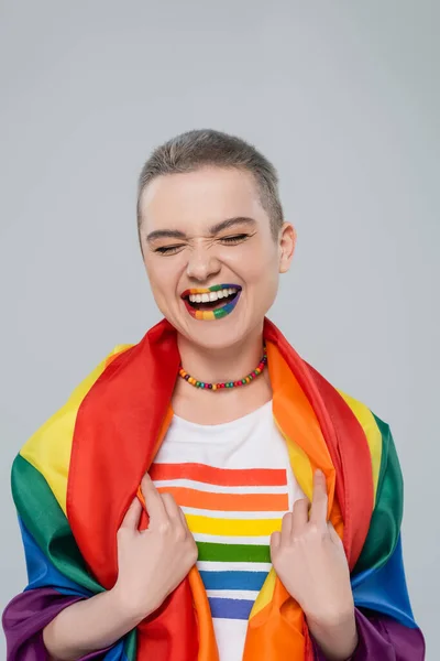 Mulher feliz com bandeira lgbt e lábios em cores do arco-íris rindo isolado em cinza — Fotografia de Stock