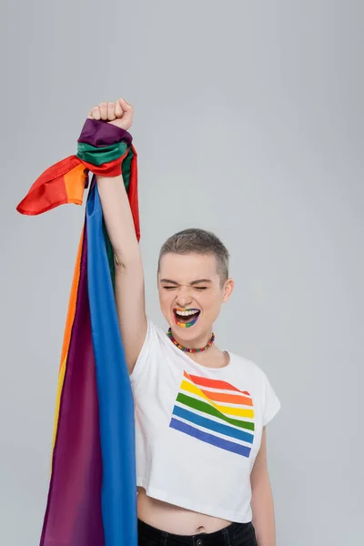 Aufgeregte Frau mit erhobener Hand in grau — Stockfoto