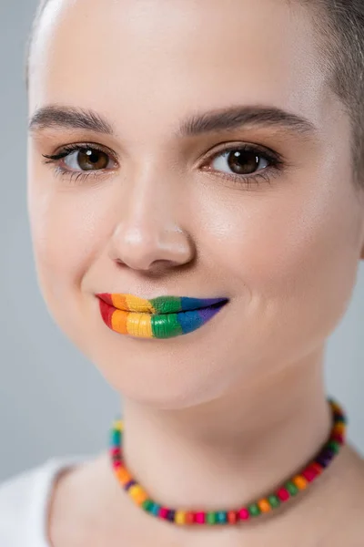 Nahaufnahme Porträt einer lächelnden Frau mit regenbogenfarbenen Lippen, die in die Kamera schaut, isoliert auf grau — Stockfoto